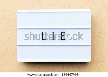 White lightbox with word lie on wood background