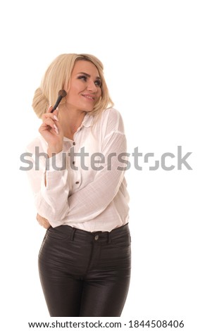 Beautiful blonde woman with makeup brush posing on camera. Girl standing on a white background with a makeup brush. 