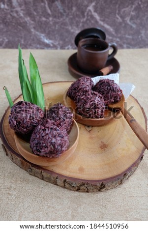 picture of sticky rice balls which put on wooden plate.its taste is sweet and sour,behind the foods,there is beverage which put on a brown cup.selective focus