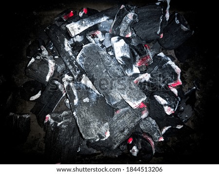 Group of charcoal pieces burning into ashes.