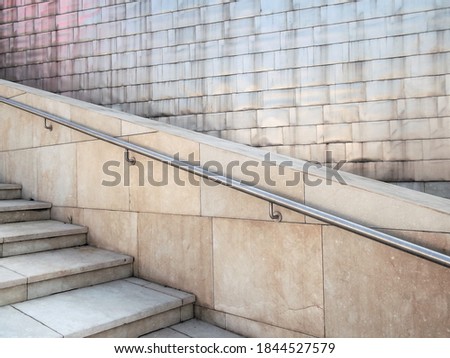Detail of a stainless steel handrail, titan tiles for the facade and marble staircase