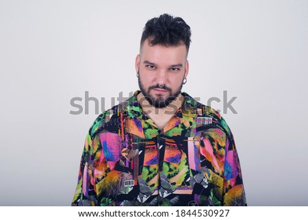 Portrait of outraged young man wearing generic design shirt  frowning his eyebrows being displeased with something. Scowling pretty female isolated over grey.