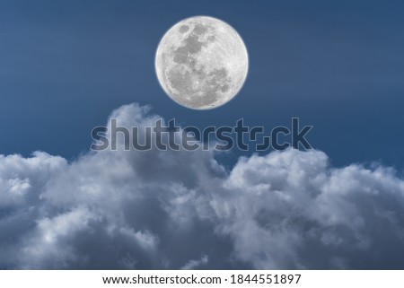 Full moon over clouds on the sky.