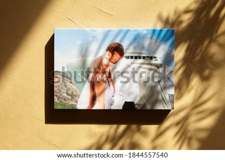 Wall with photo printed on canvas. Canvas print, wedding photo on wall with sun light and shadow of leaves