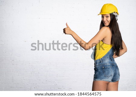 Thumb shown up. A woman in a yellow protective helmet shows that everything is fine.