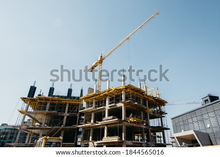  construction crane on the background of the tops of the house and the blue sky
