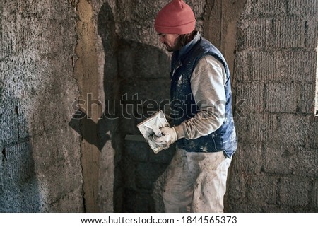 Real construction worker working on a wall inside the new house.