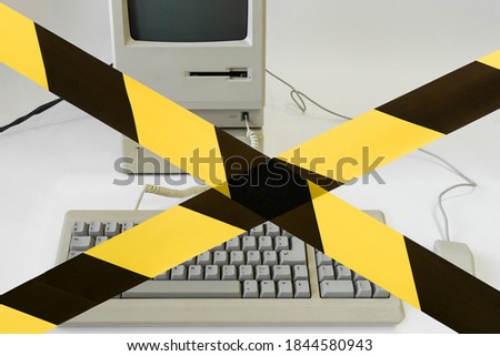 
caution tape in front of a personal computer. old desktop computer banned. Access is denied.