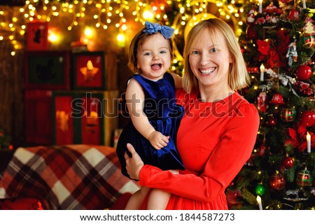 Happy family mother and child. Little daughter play in winter for Christmas holidays. A mother holds a child in her arms near a decorated Christmas tree.