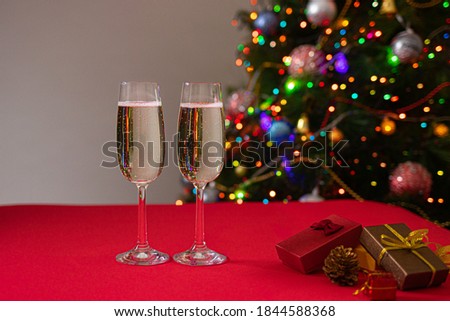 New Year's photo glasses on a red table with champagne on the background of the Christmas tree with lights and sides. Holiday and bull year