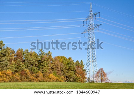 Pylon in the morning sun on the hill at the colored autumn forest.. In large parts of Germany, electricity is transported from producer to consumer with so-called electricity routes.
