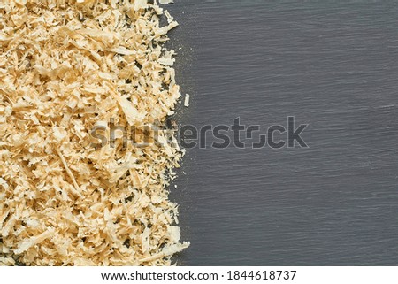 Row of scattered wooden sawdust on dark concrete surface in carpentry workshop