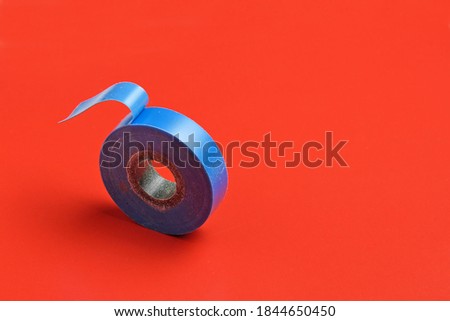 A roll of blue insulation tape on a red background close-up