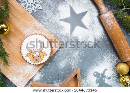Greeting card for the New year. Gingerbread bull as a symbol of 2021. Christmas tree, cookies, flour on a dark background. Christmas, happy new year 2021. New year's food. Space for text.