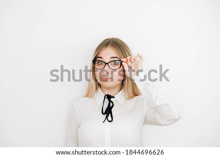 Portrait of a positive beautiful blonde woman wearing stylish white shirt holding her glasses on a white background. Copy, empty space for text