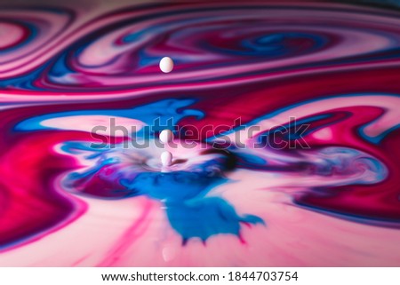 Drop falls into colorful paint surface