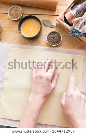 Woman hands cutting a rectangular puff pastry. Royalty-Free Stock Photo #1844712937
