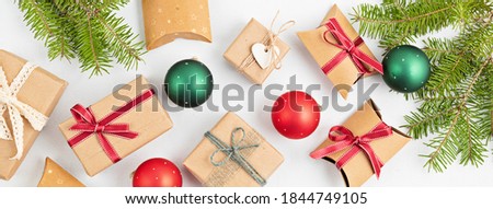 Banner with Assortment of paper wrapped Christmas gifts, and red and green baubles with pine branches on white background, flat lay, top view