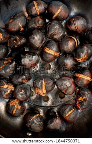 Photography with selective focus on the ingredient, pan over direct fire to roast chestnuts, Catalan tradition of "the chestnut"