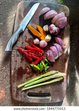 Food preparation of Masak Lemak Cili Api consists of onions, garlic, chilies, tumenic and lemongrass on a cutting board . Food photography