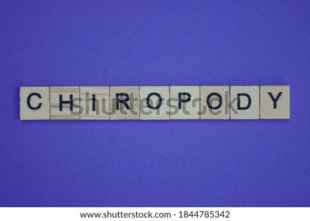 gray word chiropody in small square wooden letters with black font on a lilac background
