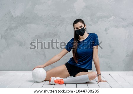 Young woman protective face mask with volleyball ball isolated on grey background. Protective masks against virus infection. Vintage color filter