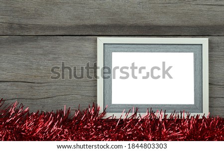 Empty vintage photo frame on wooden floor and red tassels for Christmas and New Year decorations.