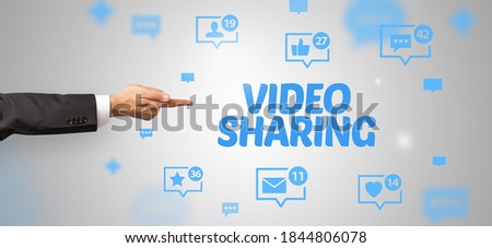 Close-Up of cropped hand pointing at VIDEO SHARING inscription, social networking concept