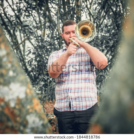 
trombonist musician playing his musical instrument in nature