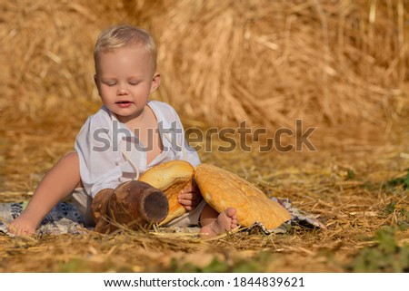 A small village boy in the hayloft with a jug and homemade bread.