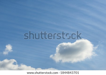 Cloudscape of fluffy clouds and long wispy clouds against a blue sky, as a nature background
