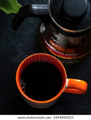 Orange coffee cup mug and coffee server in a black stone dark coffee fresh roasted hot drink cafeteria caffeine