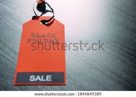 Red tag with inscription on dark wooden background in stylish design, close-up. Concept of black Friday. Final sale in America. Season of total discounts. Image for advertising with copy space.
