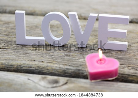 Candle with with text on wooden background, closeup.