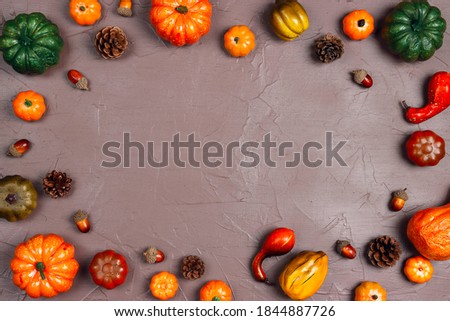 Frame of decorative pumpkins and acorns on brown background. Copy space for text. Halloween, Thanksgiving day or seasonal autumnal background. 