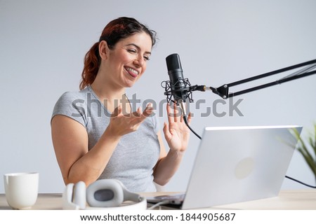 A charming woman radio host is broadcasting live on a laptop. Online radio concept