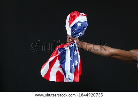 Close up of black mans hand holding American flag isolated on black background. Concept of patriotism, love for the Motherland, national symbol