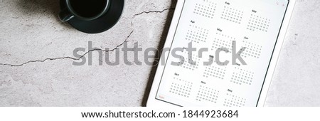 a tablet with an open calendar for 2021 year and a cup of coffee on a gray concrete background. banner