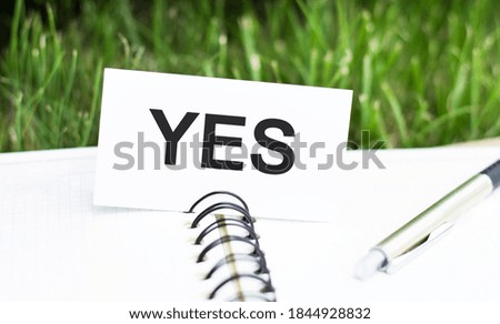 text YES on a white card lying on an open notebook. Business concept