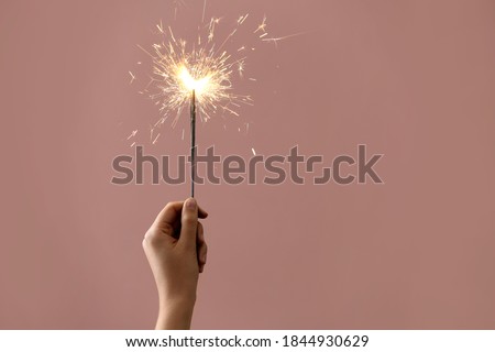 Woman holding burning sparklers on pink background, closeup. Space for text Royalty-Free Stock Photo #1844930629