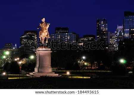 George Washington statue in Boston Public Garden at night against deep blue sky and city skyline background.