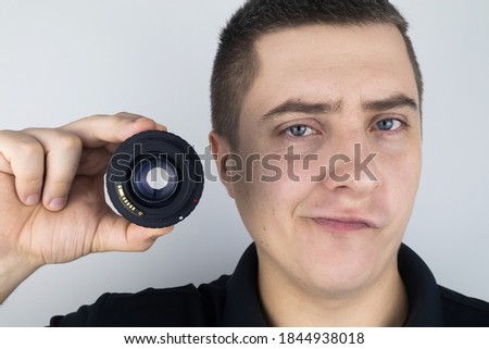 Male photographer is holding a lens near his face and smiling. The joy of creativity. Happy photographer and creative concept.