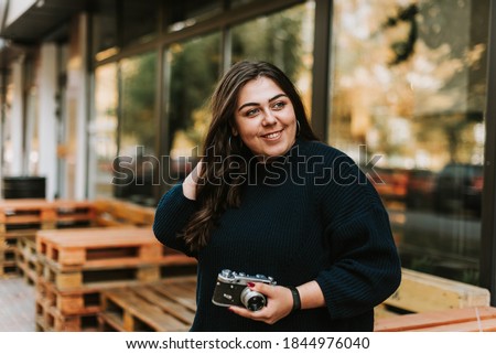 Portrait of young adult girl holding vintage camera outdoors