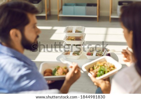 People eating healthy food at home or in office and discussing set of meals for the whole day. Stack of ordered and delivered takeaway containers with fresh breakfast, lunch and dinner in soft focus Royalty-Free Stock Photo #1844981830