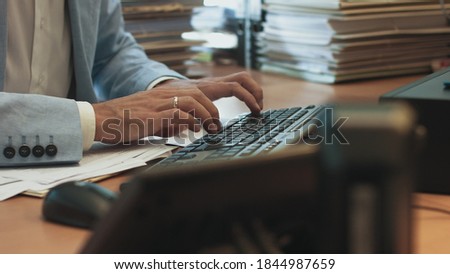 Pan Shot of Businessman hands typing on desktop computer keyboard for searching information, marketing research, online communication support and make a business report in the office desk at night.