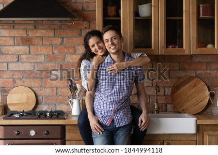 Portrait of happy millennial couple renters tenants relax in own modern kitchen moving in shared home together. Smiling young Caucasian family buyers excited about new dwelling. Real estate concept.