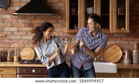 Wide banner view of happy millennial man and woman renters buyers celebrate moving to new shared house together. Overjoyed young Caucasian couple tenants have fun dancing on weekend in own home.