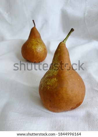 Two pears on white linen table cloth background. Still life style art photography.