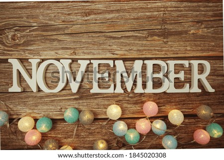 November alphabet letter with LED cotton balls on wooden background