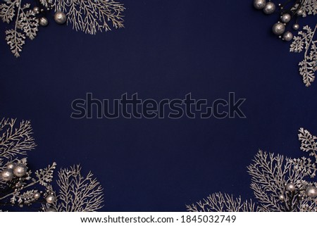 Frame made of silver branches with leaves on blue background. Flat lay, top view, copy space. Christmas or new year glitter composition. Place for text